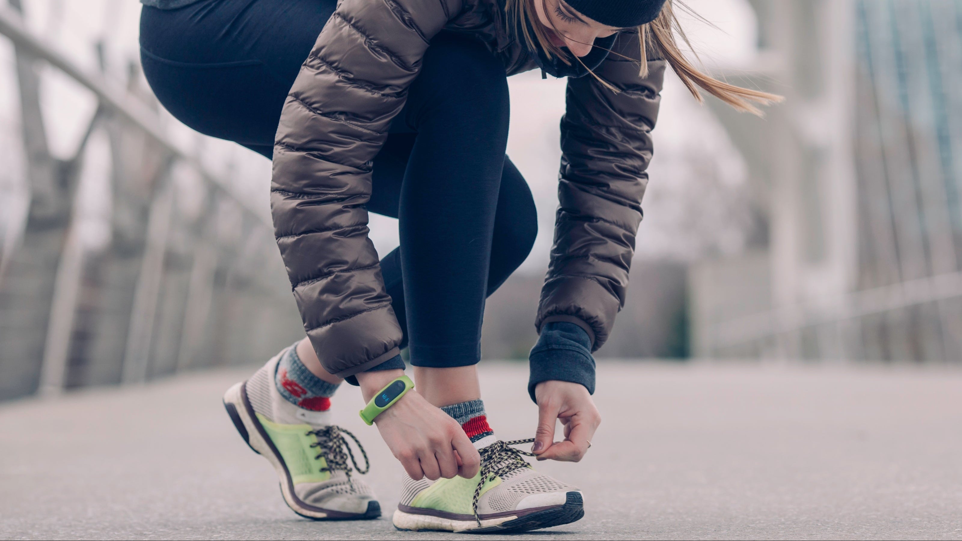Person tying running shoes on a bridge